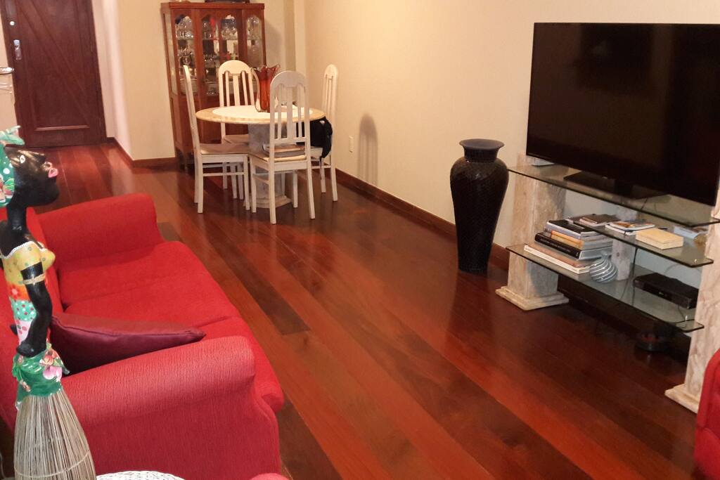 sala com sofá de 2 lugares e dois sofás para uma pessoa. tv de 50p a cabo, mesa de jantar para 4 pessoas, ar condicionado e varanda privativa