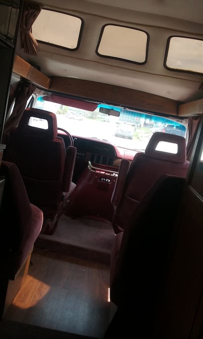 Front of motorhome with 2 captains chairs that rotate and convert into 2 single beds.