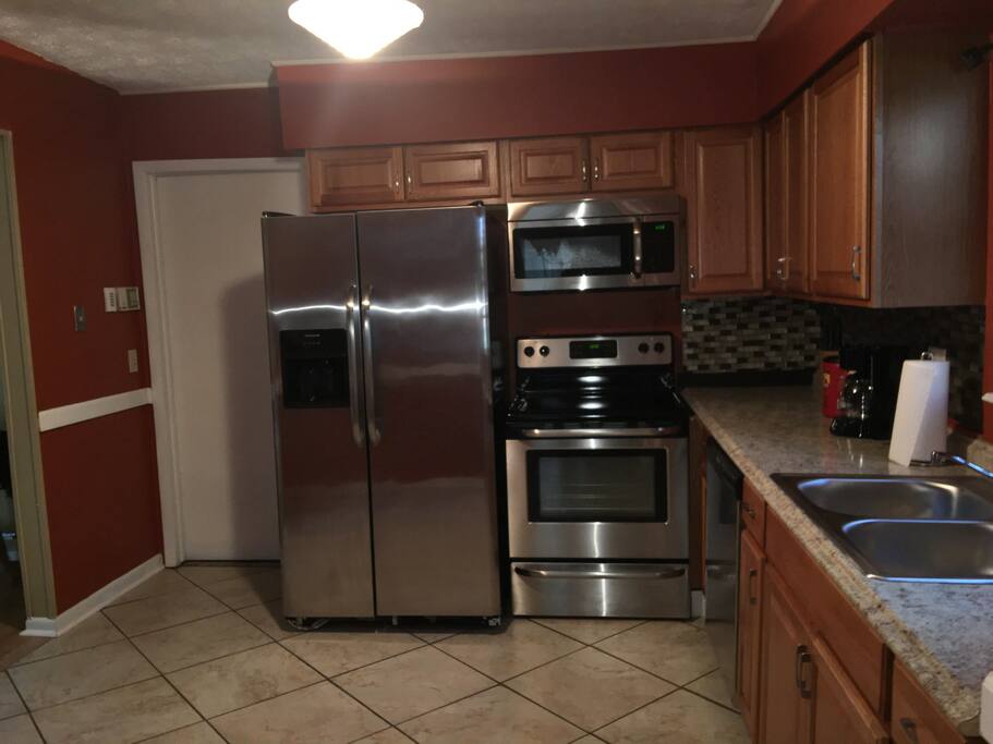 Kitchen with brand new stainless steel appliances refrigerators stove micro wave dishwasher coffee maker toaster and lots of cabinets with luxury back slash.