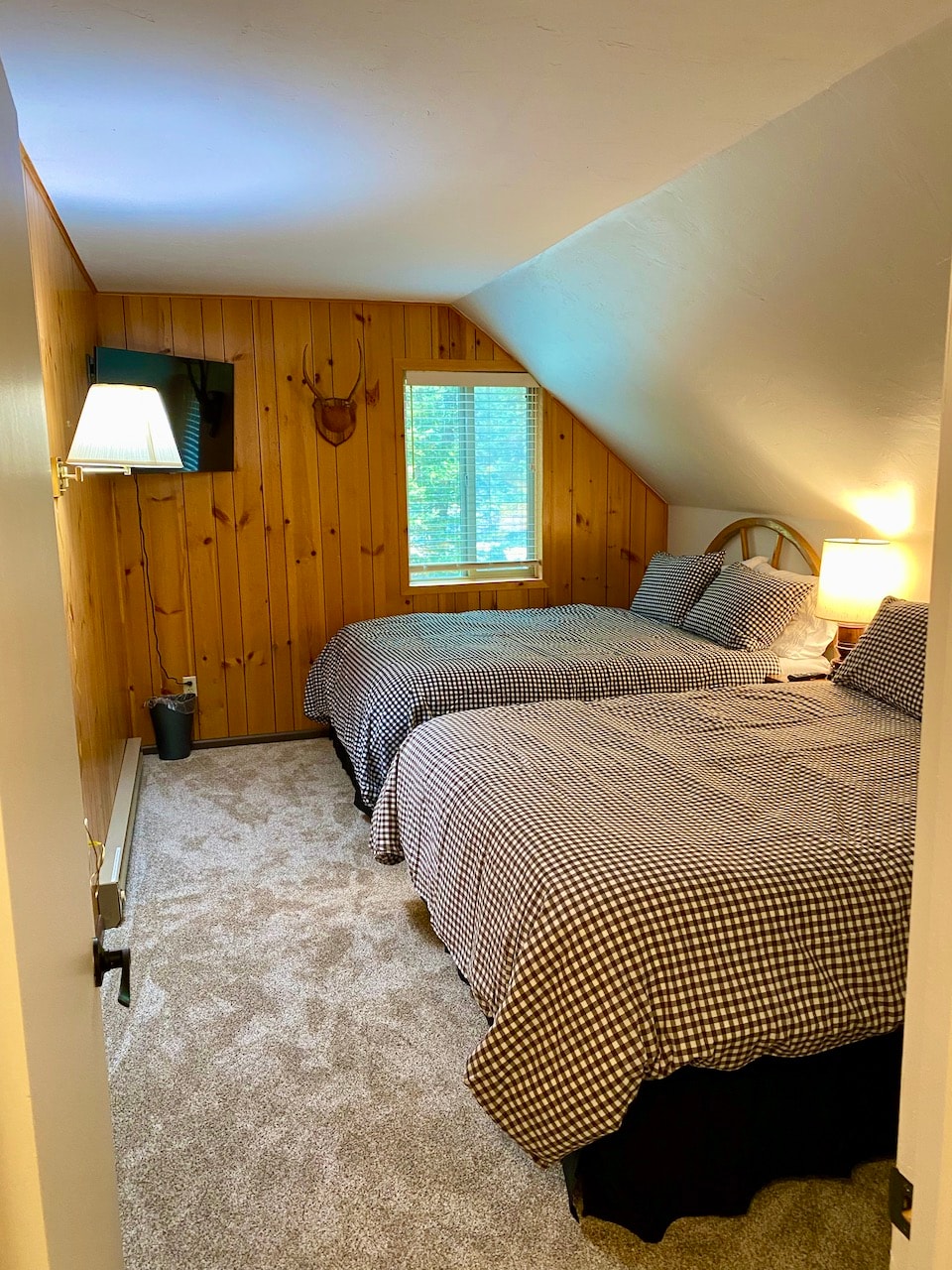 An upstairs bedroom with two queen beds in a straightforward layout, providing basic sleeping space for guests.  