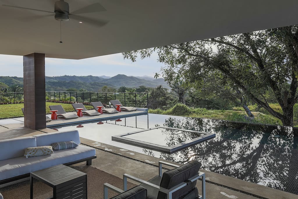 Exterior - Pool area complete with lounge chairs, hot tub in the middle of the infinity pool
