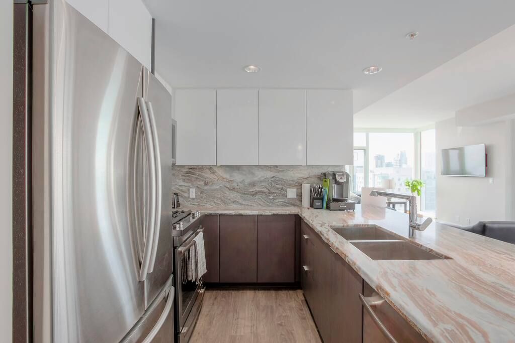 Looking into the kitchen, note the Keurig 2.0 machine and descent knife block available for use down from the large stainless steel sinks that have a garburator.