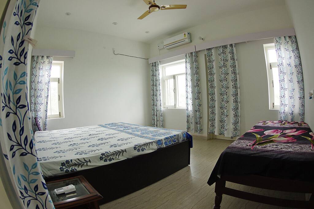 Spacious bedroom with Godrej Interio twin bed which is 6 1/2 ft long and features a Godrej Interio orthopedic mattress. You can see Pong reservoir from the windows. A patio outside lets you observe birds from close quarters.