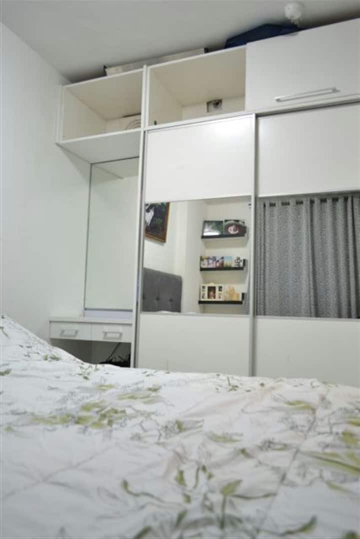 Main bedroom, with hotel-standard Slumberland bed, air conditioner, and large wardrobe.