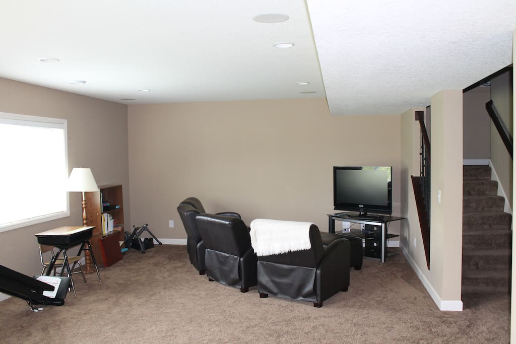 Basement entertainment area with television, seating for four, and exercise equipment