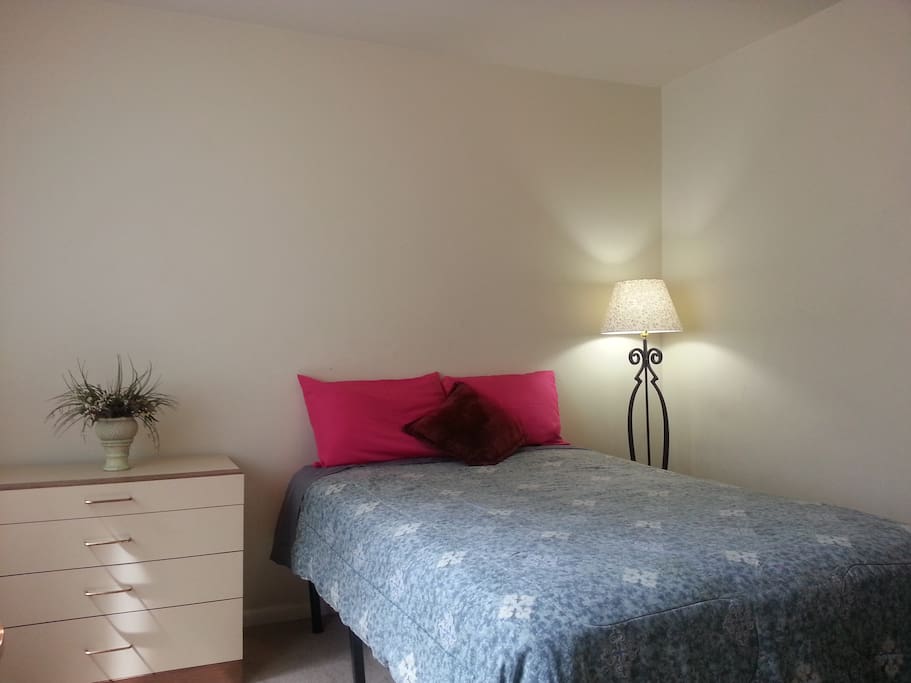 This room has a full size bed, dresser, floor lamp and a closet
