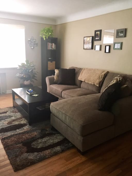 Living room with a spacious sectional couch, TV, and view of downtown Denver!