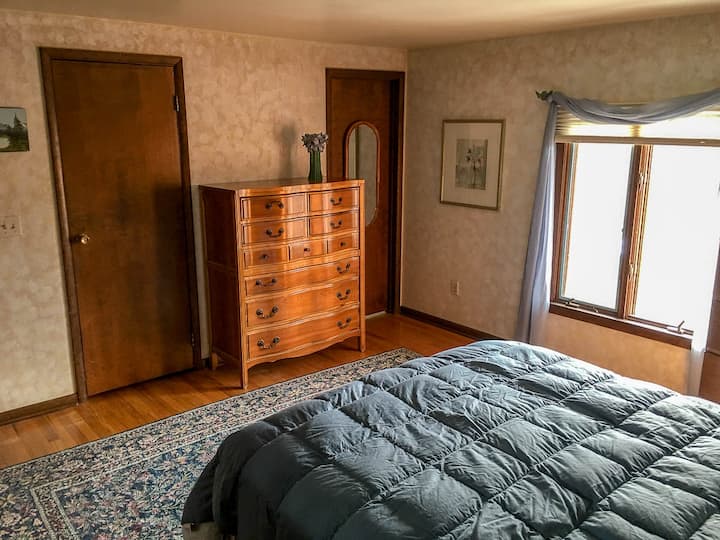 إطلالة أخرى على غرفة النوم الرئيسية. توجد خزانة ملابس كبيرة وخزانة ملابس.  الحمام الرئيسي على اليمين في الصورة. يوجد تلفاز لمشاهدته في غرفة النوم هذه. 