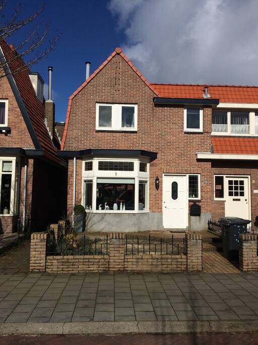 Het zonnige jaren 30 huis met de voortuin en de poort naar de achtertuin.