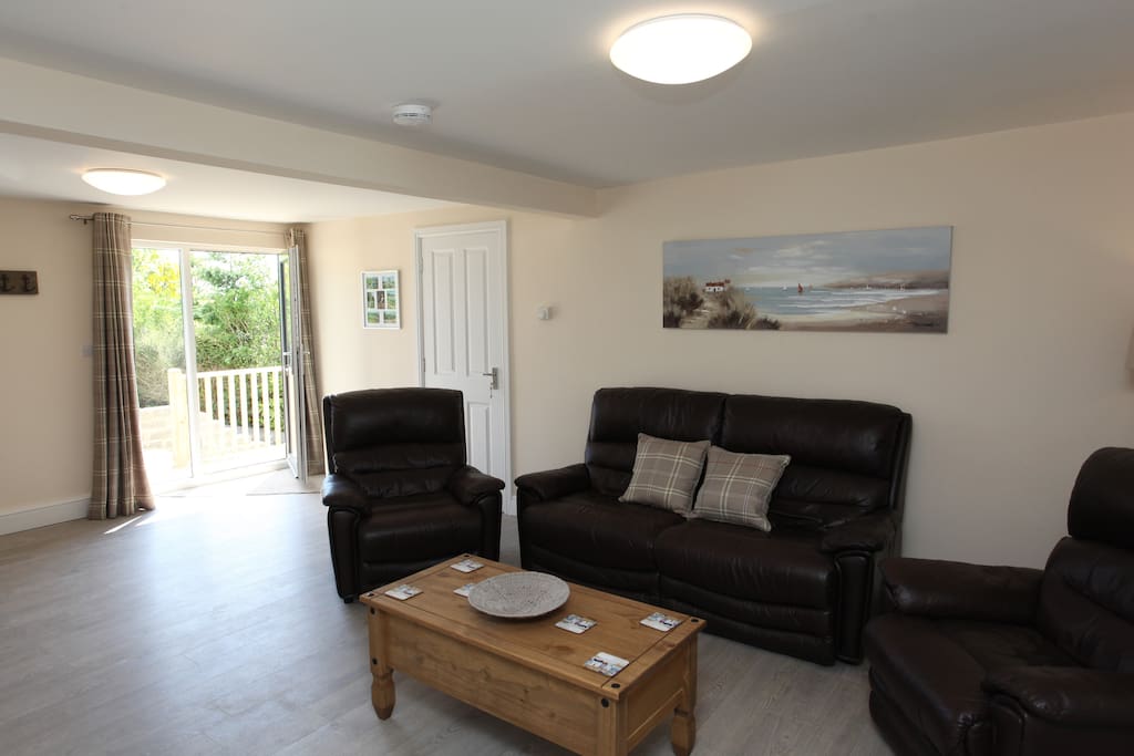 Very comfortable open plan living area with sofa and arm chairs.