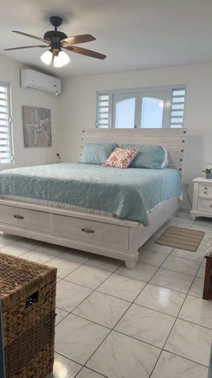 Dormitorio principal con cama King y baño adjunto. Viene con aire acondicionado, mesitas de noche con puertos de carga USB, ventanas de privacidad esmeriladas y persianas oscuras de la habitación.