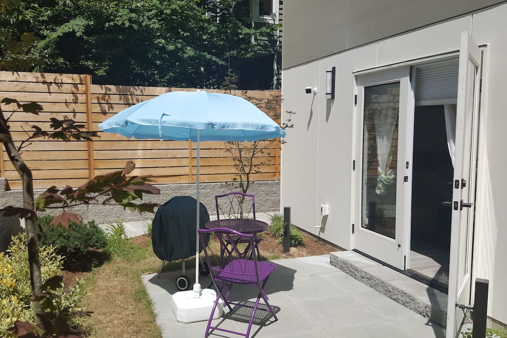 Patio room includes a charcoal grill, bistro table and umbrella.
