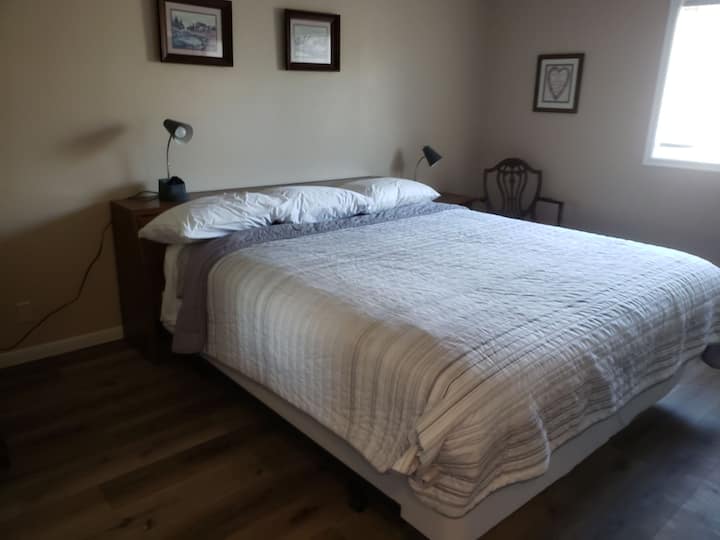 سرير كبير في غرفة النوم الرئيسية. يحتوي أيضًا على خزانة ملابس ، وخزانة ملابس ، وتلفزيون.