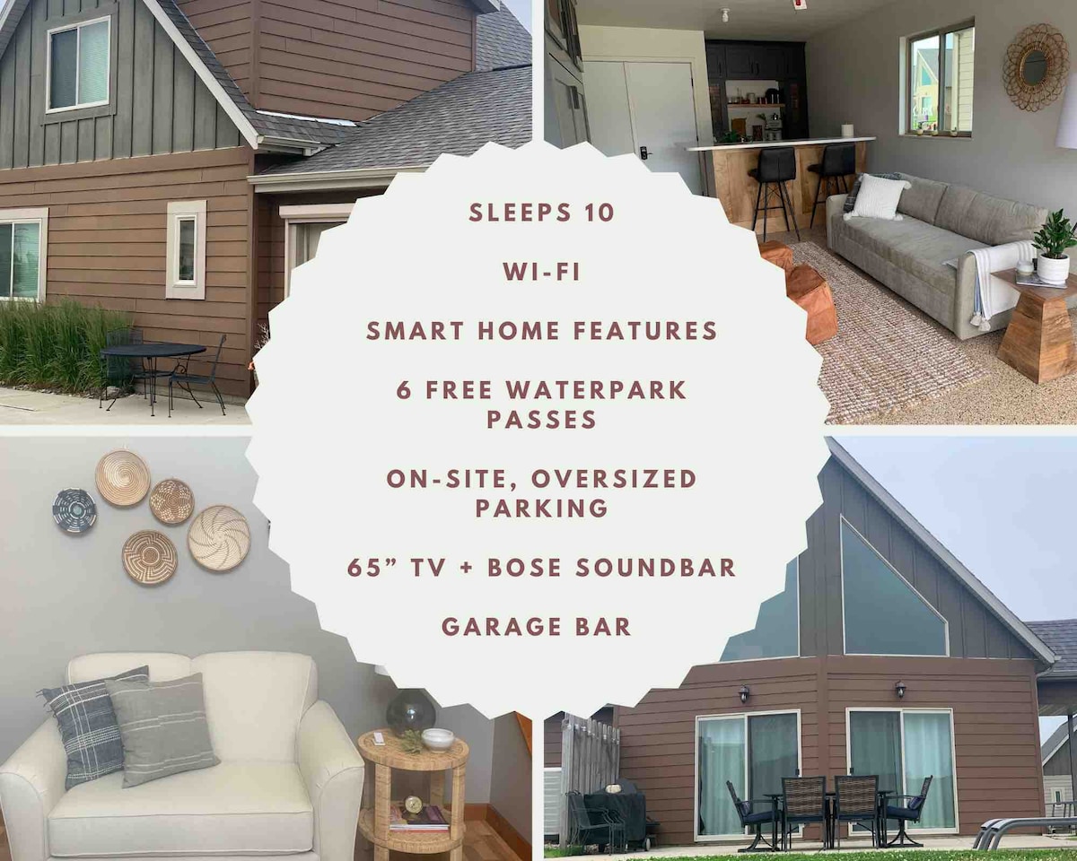 The cabin's exterior showcases a modern brown facade with white trim. An outdoor lounging area can be seen, with a cozy seating arrangement visible inside. Additional features include a garage bar and a spacious driveway for convenient parking.