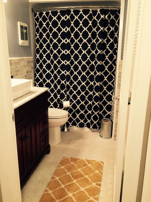 Beautiful new bathroom with marble tile on the floors and walls. The cabinet is made from cherry wood and topped with carrera marble.