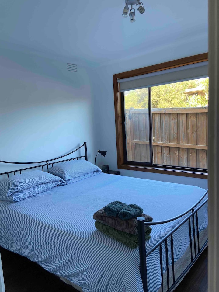 חדר שינה למטה. מיטת קווין סייז, שולחן צדדי וארונות בגדים. 