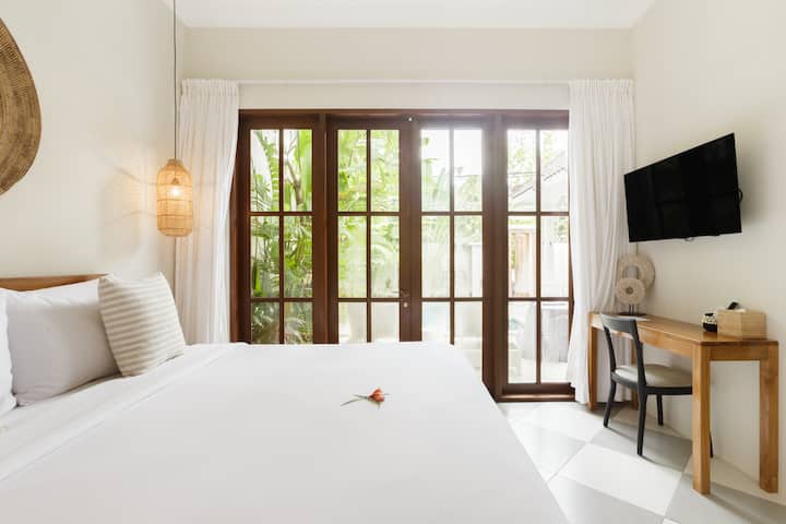 Një dhomë gjumi moderne ka mobilie elegante, dekor elegant dhe një dritare të madhe që e mbush hapësirën me dritë natyrale.