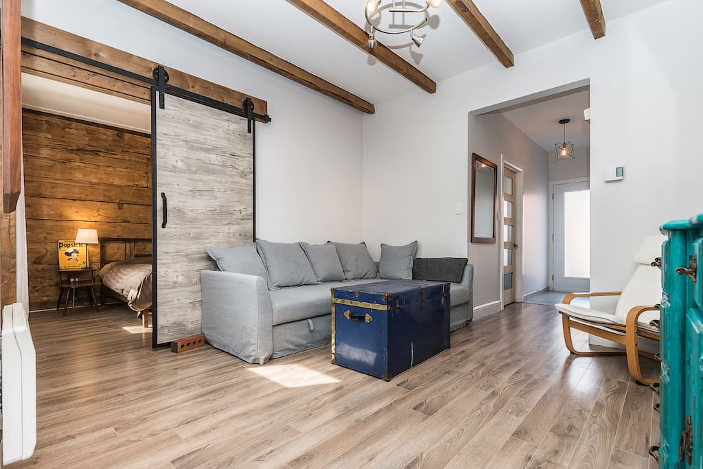 Exposed wood beams and sliding barn door leading to second bedroom
