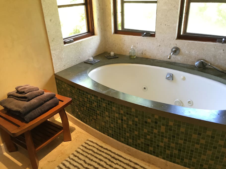 Two-person soaking tub with comb shower and coral tile trim.