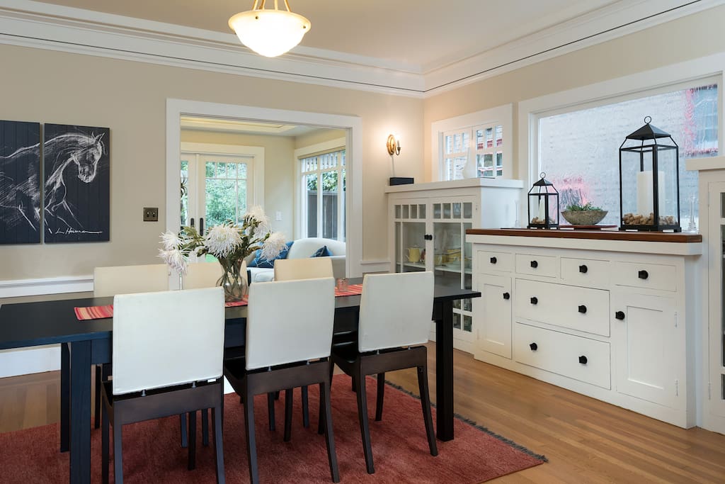 Beyond the living area is the formal dining area, also elegantly furnished and light-filled, with the kitchen in the background