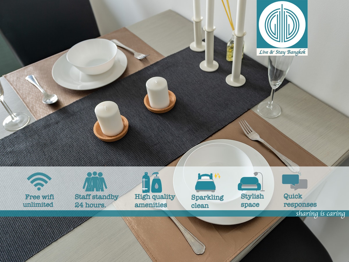 A well-set dining table displays two plates and glasses with two candles in the center. Placemats of contrasting colors are used, and the setting emphasizes a clean and organized appearance, providing a welcoming atmosphere for meals.