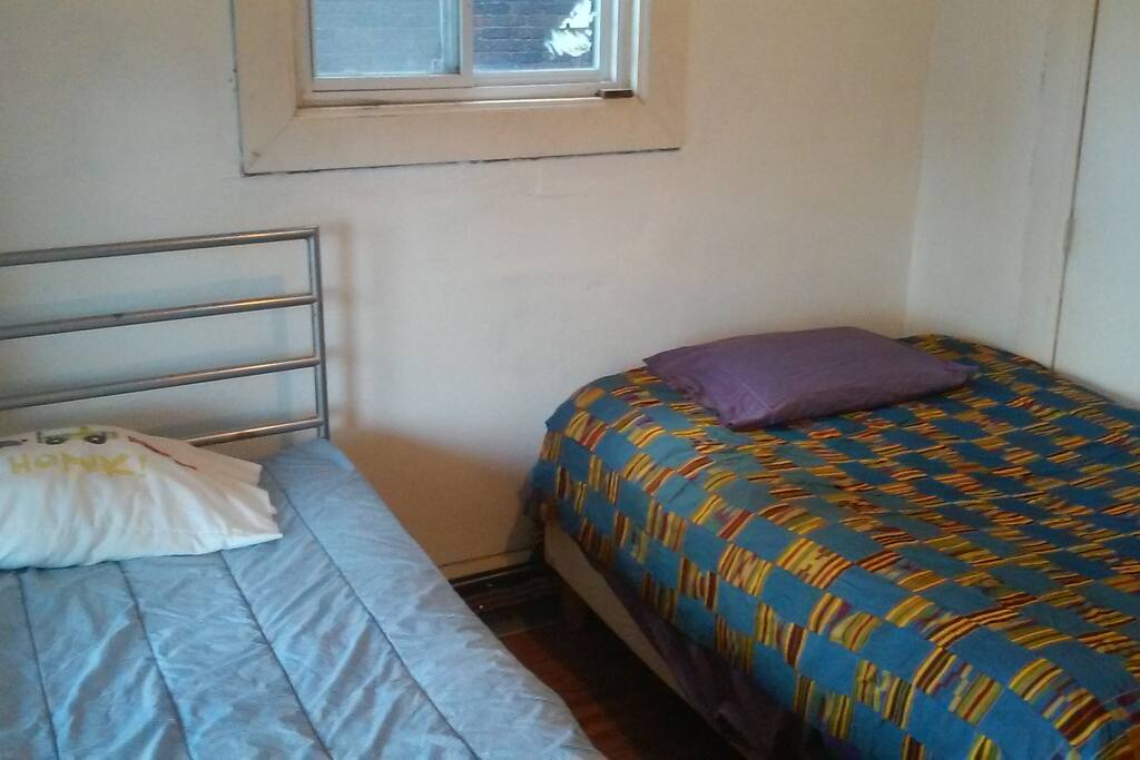 Single bed at left and double on right. Dresser is at other end of room.
