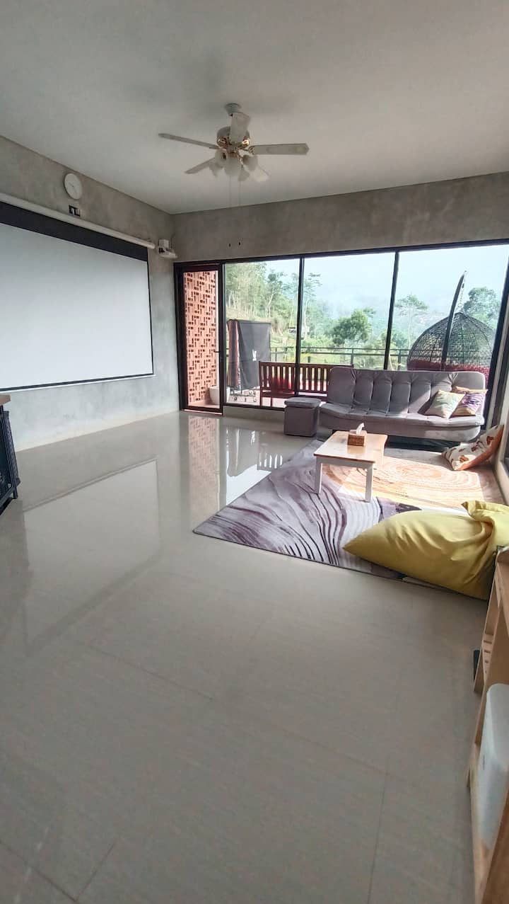 Просторна и уютна стая за развлечения, където можете да гледате филми от голям екран, с удобен диван и големи възглавници