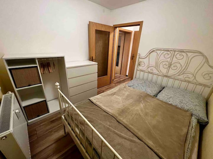 The second bedroom is practically furnished with a cozy bed, a dresser and a wardrobe to store everything necessary. The soft colors and simple design create a calm atmosphere.