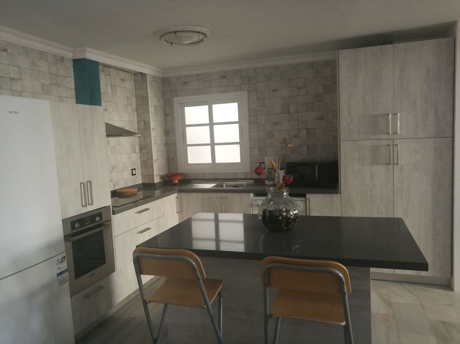 Cocina diáfana abierta al salón con isla, vitro, lavavajillas y todo lo necesario.