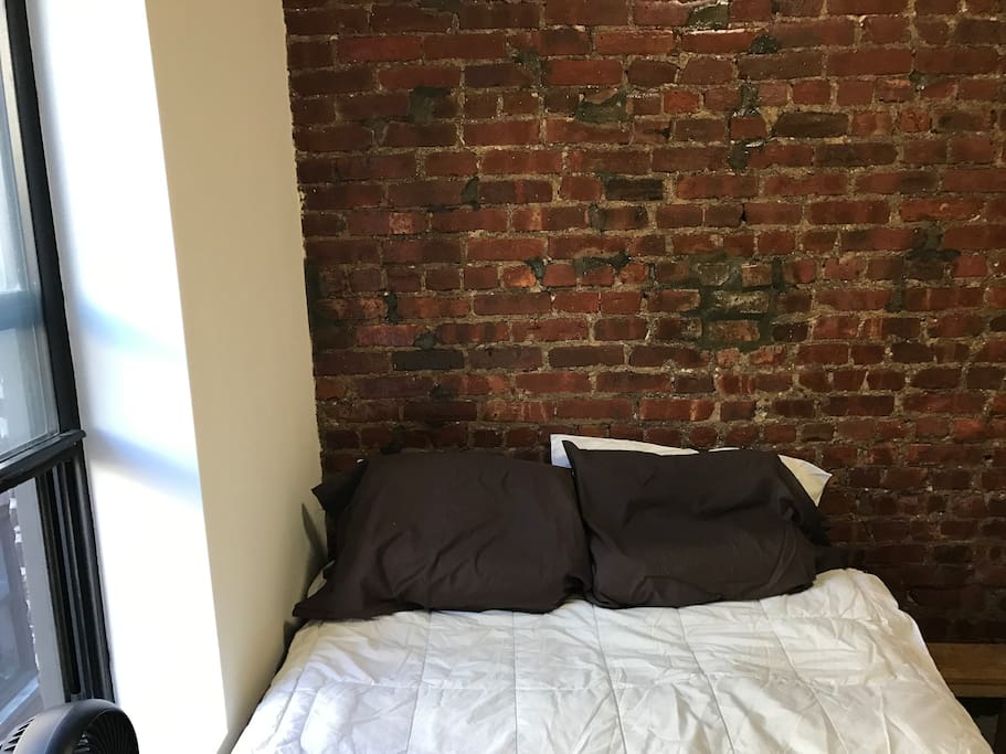 Cozy private bedroom with exposed brick makes this the quintessential NYC apartment.