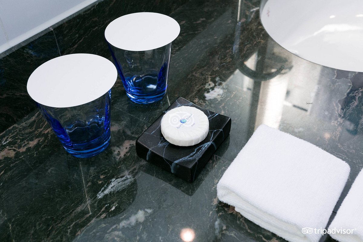 A marble countertop displays two blue glasses alongside a black soap dish featuring a white soap. A folded white towel is placed nearby, highlighting the clean and organized bathroom amenities.