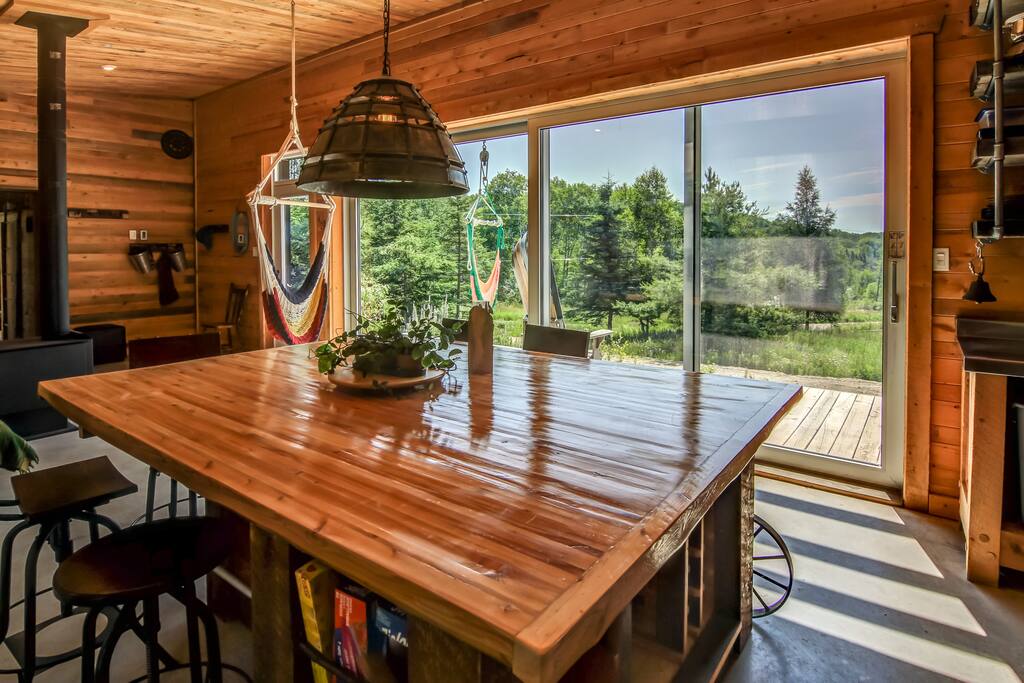 Un mur presque complétement recouvert de fenêtres laissant entrer la lumière chaude du soleil au chalet.