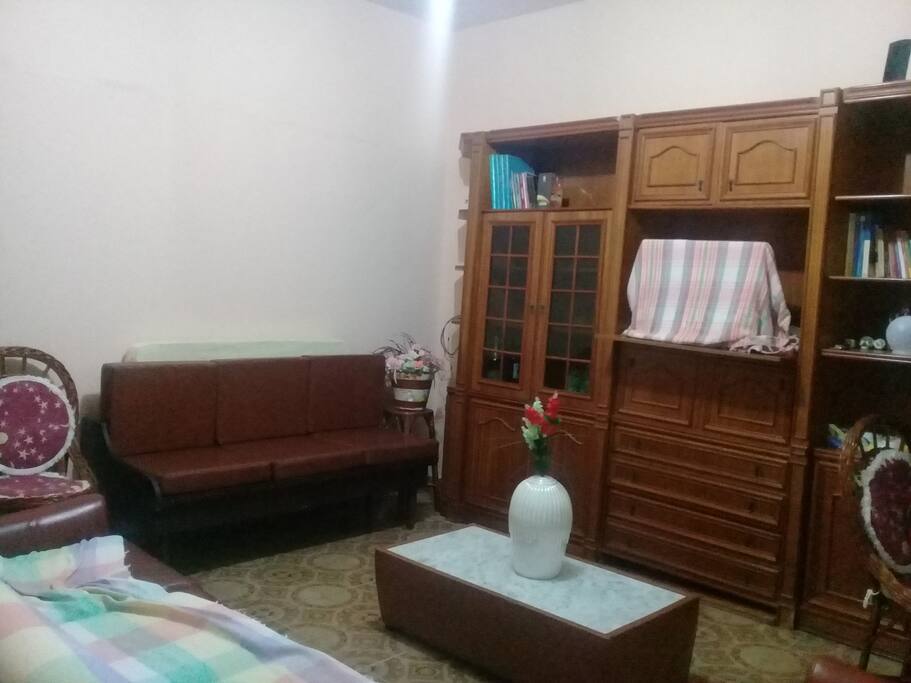 ampla sala com sofás, poltronas, mesinha, armário, ventilador de teto...