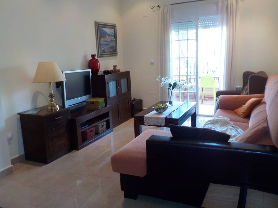 Sitting room with TV, one very confortable three sitter sofa with chaise longe, one armchair and access to the balcony. High ceilings.