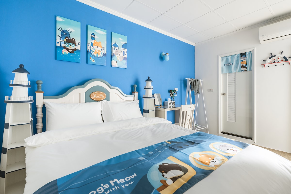 A bright blue room is featured, showcasing a spacious bed adorned with a themed blanket. Cartoon animal illustrations hang on the wall above the bed, while decorative lanterns are positioned on either side. A door with a window leads to a bright hallway.