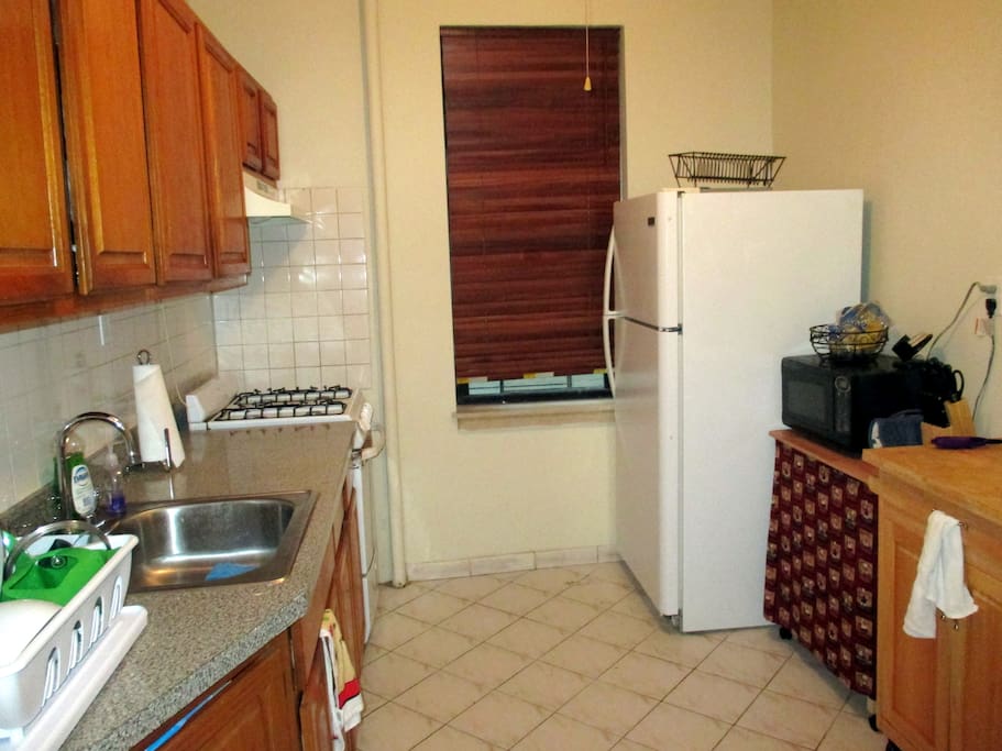Large kitchen with ample counter-space, microwave, stove, oven, fridge, dishware.