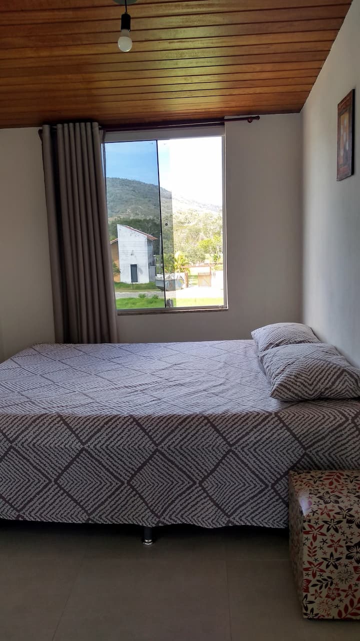 Chumba kidogo cha nje cha nyumba, chenye feni na televisheni. Hulala hadi watu 3. Inatazama eneo la kijani kibichi na mlima.