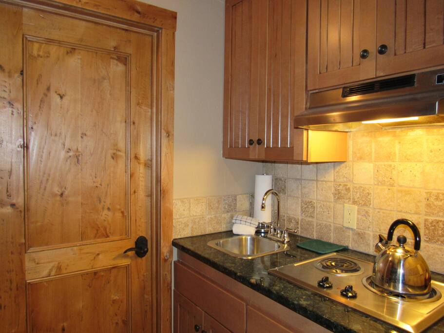 Small fully - equipped kitchen area with stove top and refrigerator