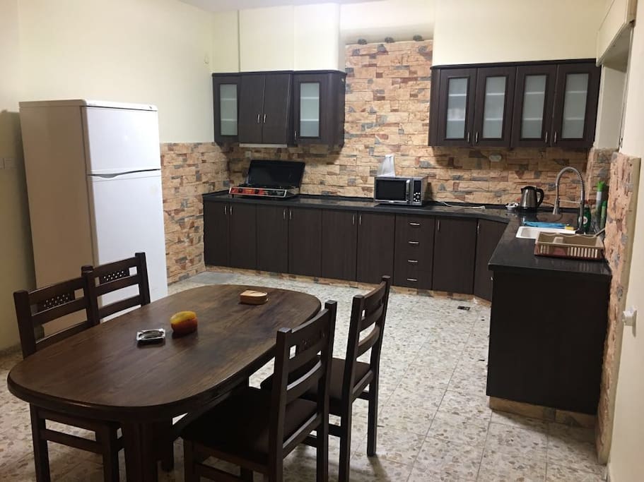 Kitchen with big fridge, microwave, kettle, gas hub and dining table
