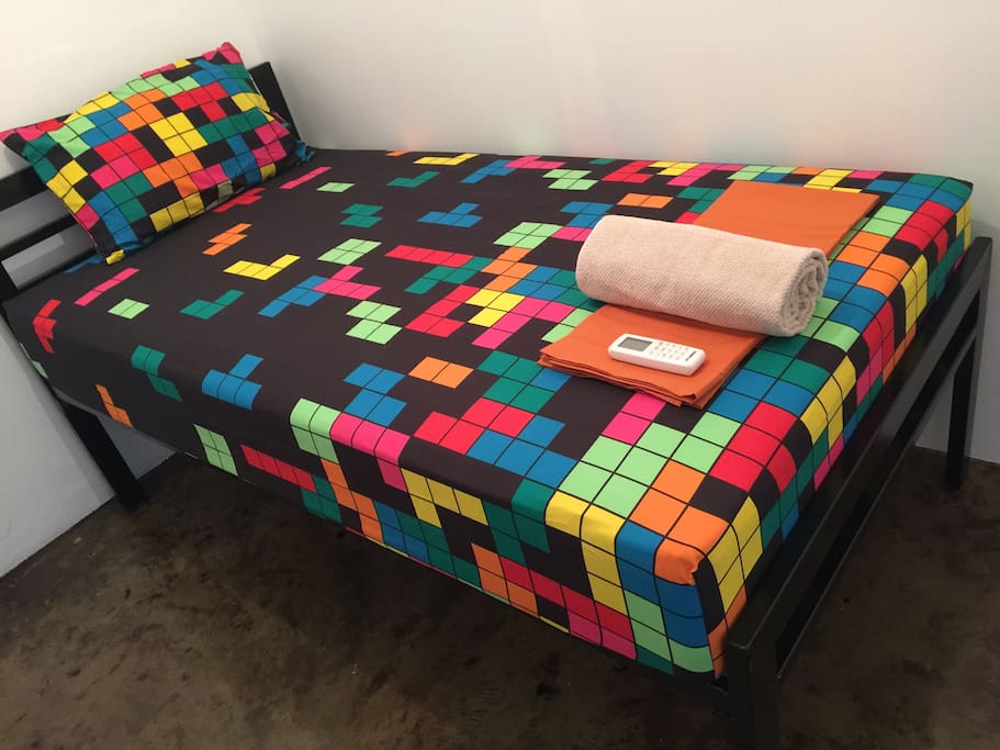 Your room! Your room comes with: 1 bed (high off the floor so your bag will easily fit underneath), 1 fitted sheet, 1 flat sheet, 1 shower towel, 1 hand towel, 1 a/c remote, 1 pillow, 1 throw pillow, 1 key for bedroom door, 1 plastic fob (blue/orange/red) for entrance door. If booked for 2 people, then 1 more shower towel. All rooms are basically the same size and shape and come with the same things just listed.