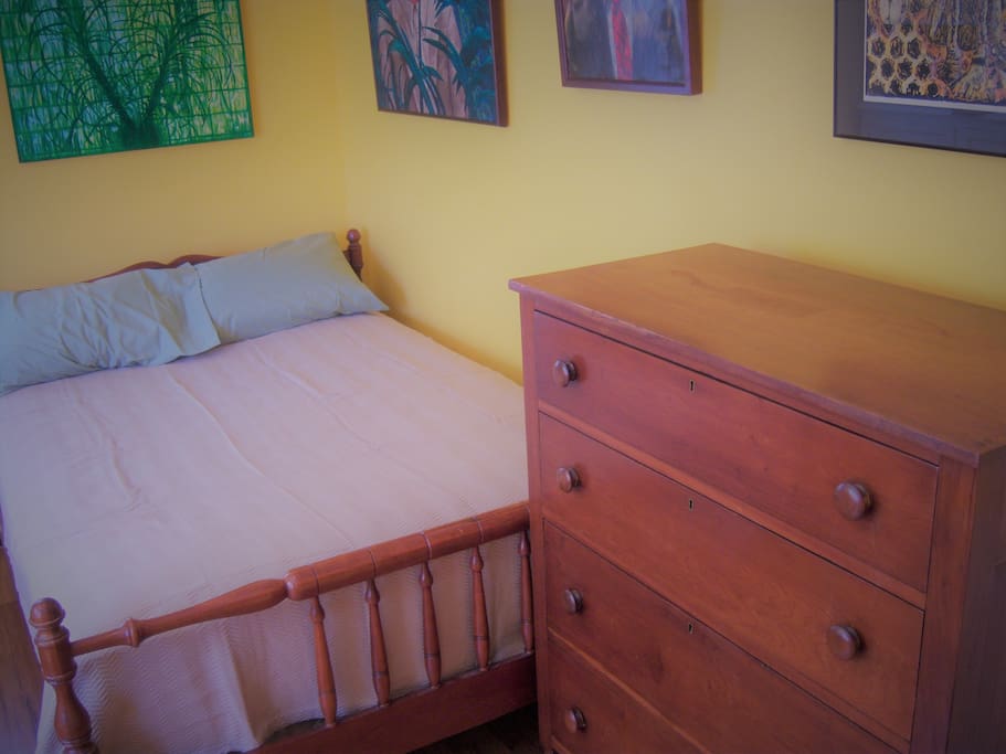The private bedroom has a queen sized bed and a chest of drawers.