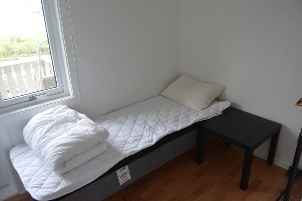 Lite soverom med en enkel seng og balkong