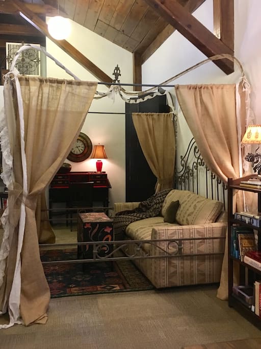 A view of the cozy hide-a-bed spot and the study desk at the rear. The sofa opens into a double bed and the curtains may be pulled for more privacy.