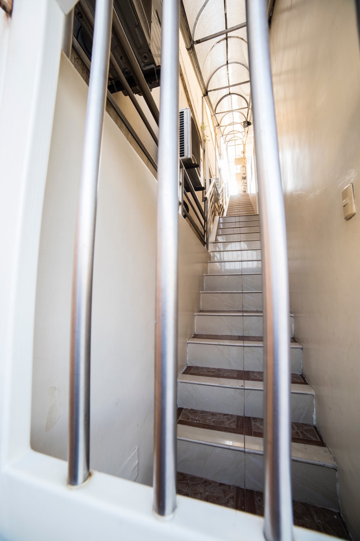 A staircase leading to the suite is visible, featuring a metal railing on the left side. The stairs are well-lit, with natural light streaming in from above, creating a warm and inviting atmosphere for guests to ascend.