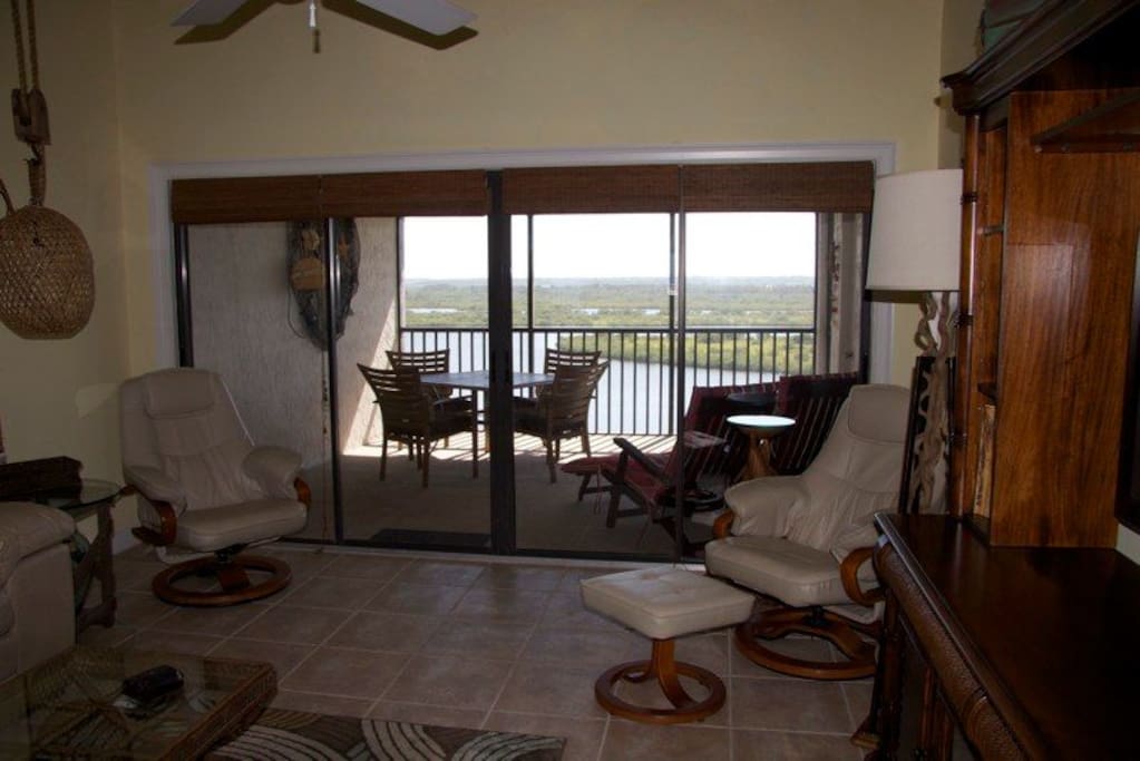 View from living area onto screened in large back patio with estuary views