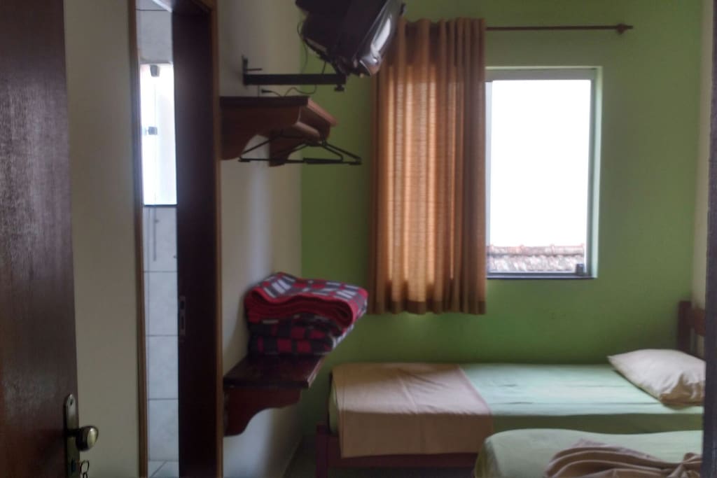 Quarto com Cama de casal e 1 solteiro, banheiro privativo, tv e ventilador.