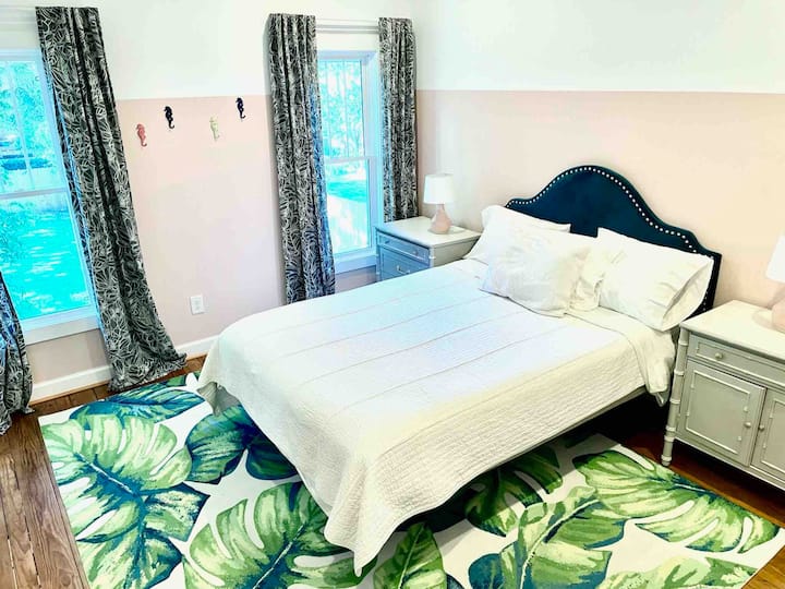 Main bedroom suite with queen Sleep Number bed, en-suite bathroom, TV, and view overlooking private backyard. 