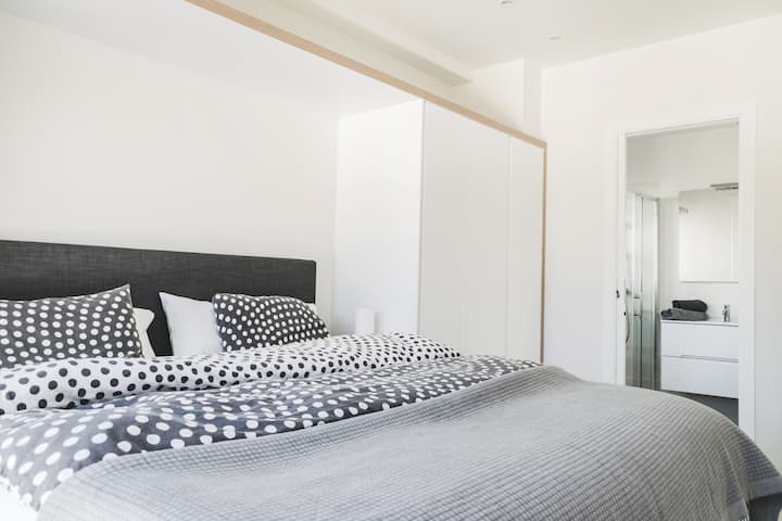 Hlavná spálňa s priľahlou kúpeľňou. 180 cm nastaviteľná kontinentálna posteľ. Skrinky na oboch stranách postele. 