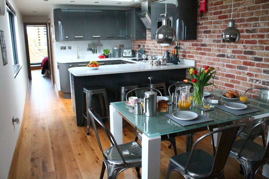 Open planned kitchen with bar stools & dining table in the foreground.