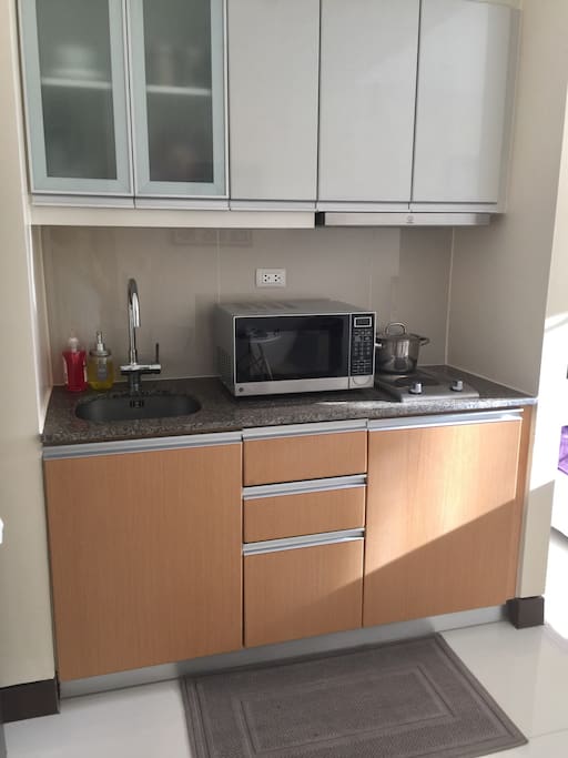 Kitchen with stove top and microwave. Plus cooking and dining utensils included